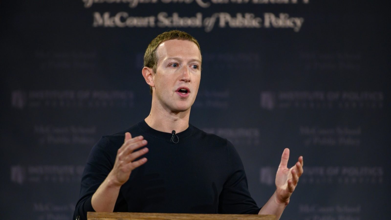 Mark Zuckerberg speaks at a lectern with a blue banner displaying 