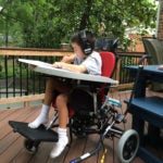 Sean Pelzel in a wheelchair on a porch outside