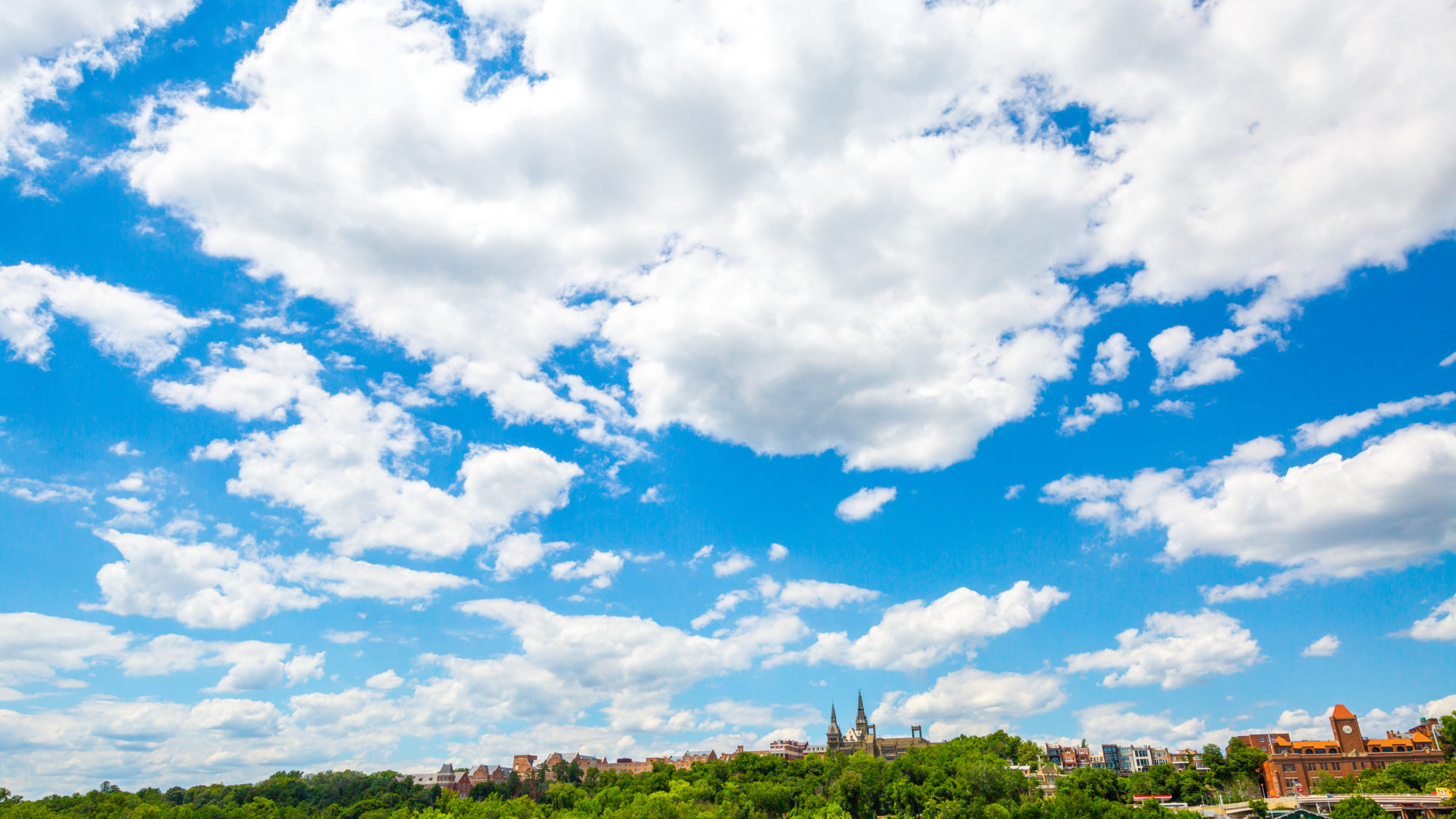 The Georgetown University campus outlines the bottom half of the photo, and is framed by a large, blue sky.