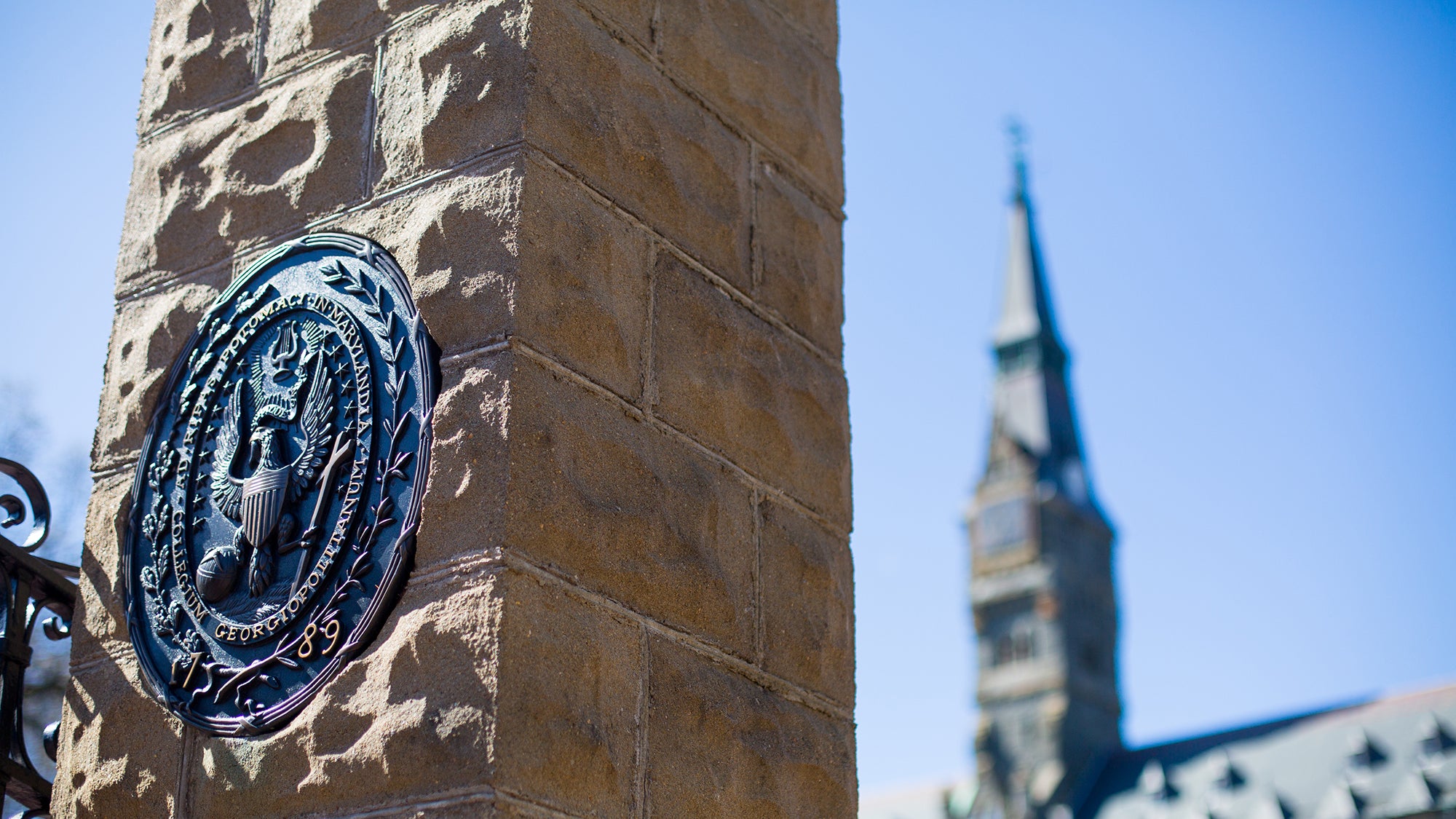 Front gates showing Georgetown seal on stone column with Healy building in the background