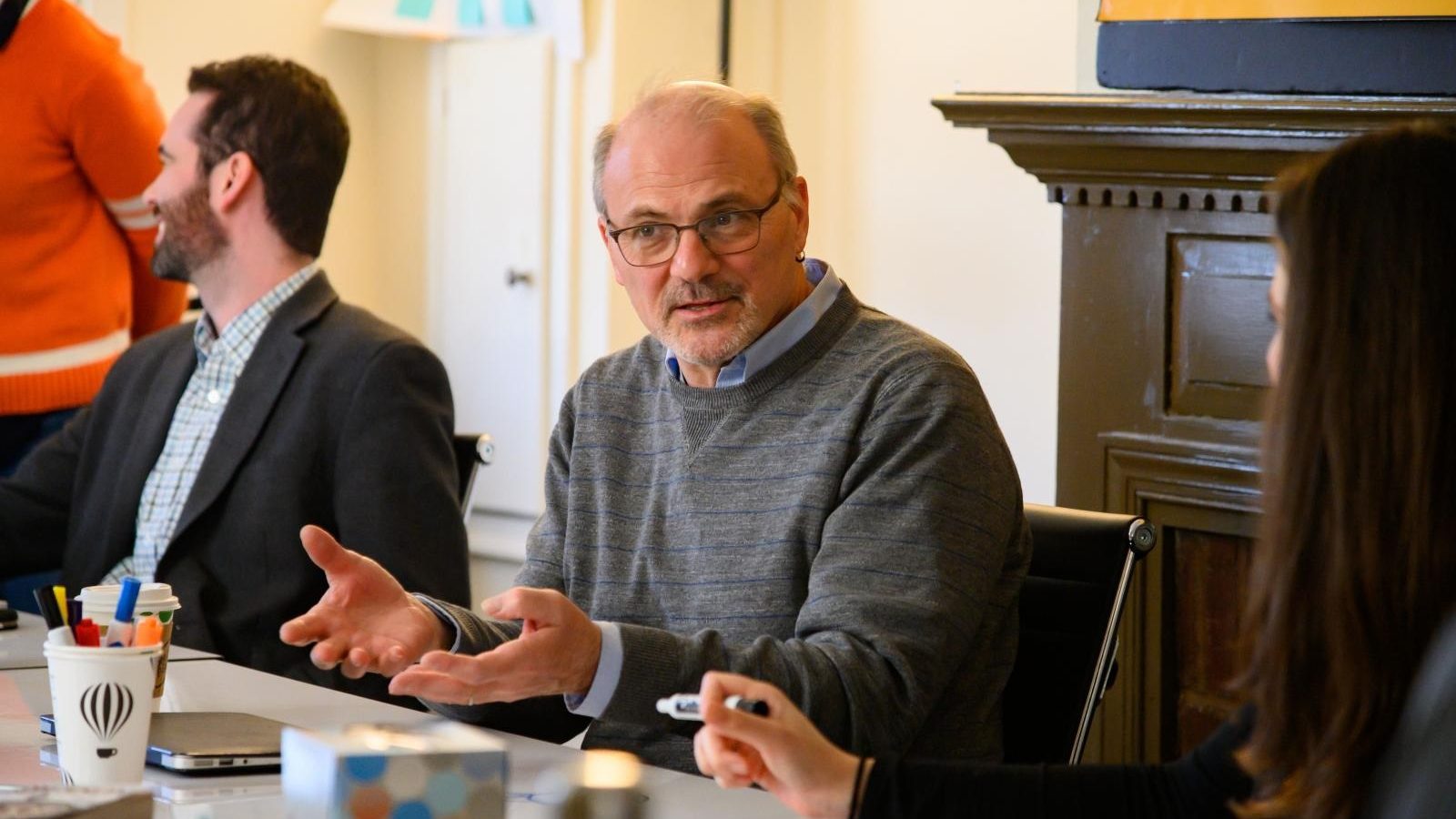 Randy Bass gestures at a table with two people sitting next to him