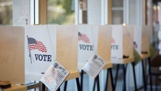 Voting booths lined up with the word &quot;vote&quot; and an American flag on them and a ballot information attached