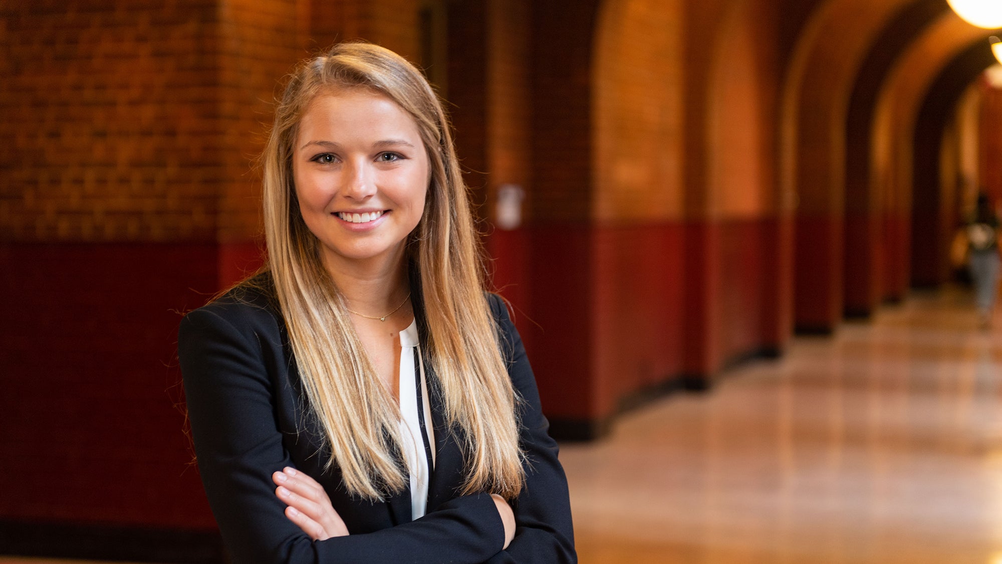 Kyra Kocis stands inside a hallway in the Healy building with her arms crossed