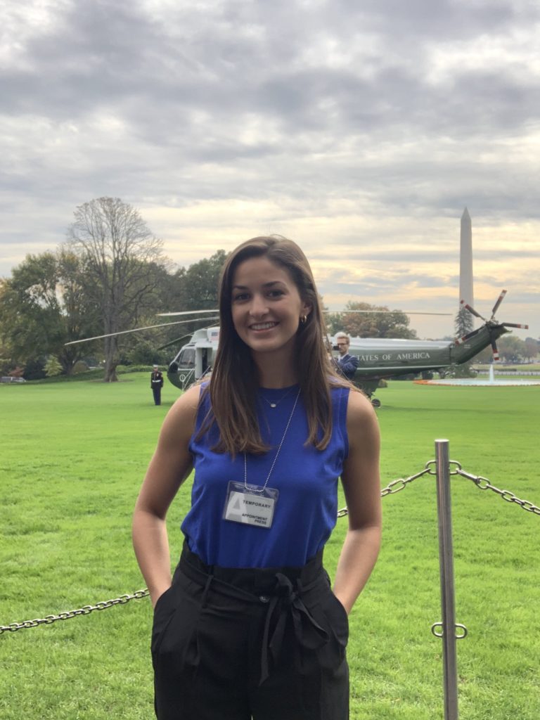 Student stands in front of the President's helicopter on the White House lawn with the monument in the background.