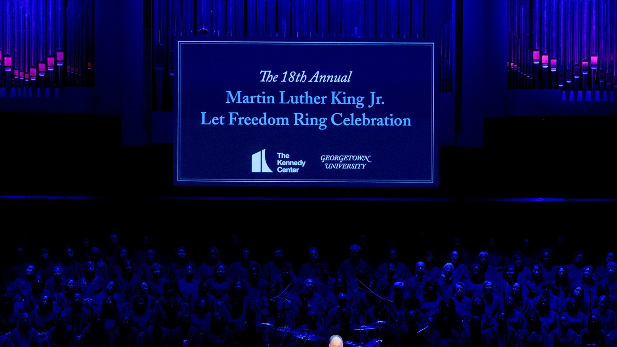 A &quot;Martin Luther King Jr., Let Freedom Ring&quot; banner hangs on a darkly lit stage.