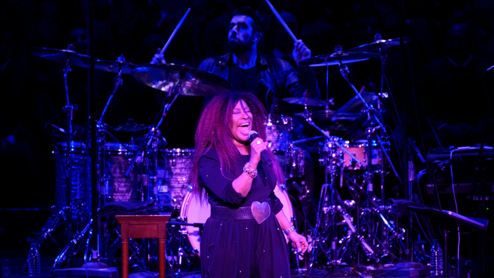 Chaka Khan sings on a darkly lit stage.