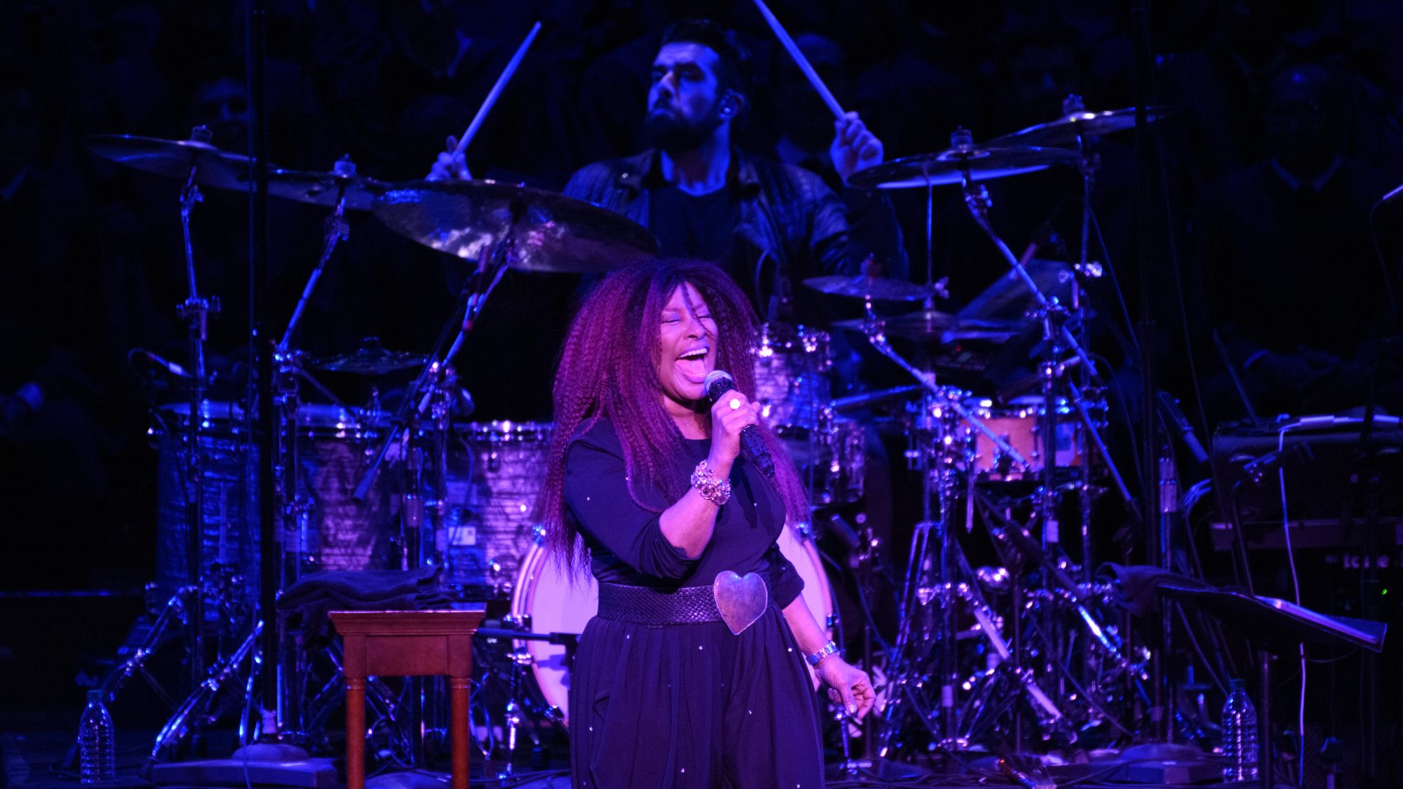 Chaka Khan sings on a darkly lit stage.