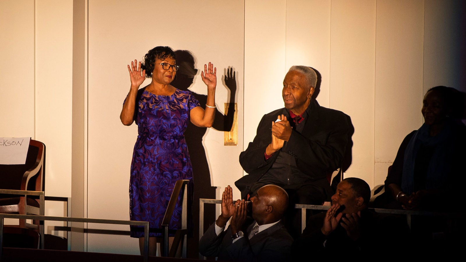 Sandra Jackson stands up with her hands up in celebration alongside a seated John Thompson Jr.
