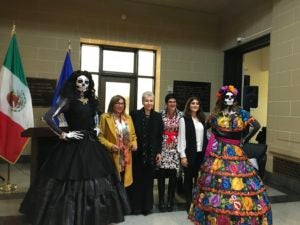 Yamel Sarquis standing with five other women, two of whom are dressed in Day of the Dead masks and costumes.