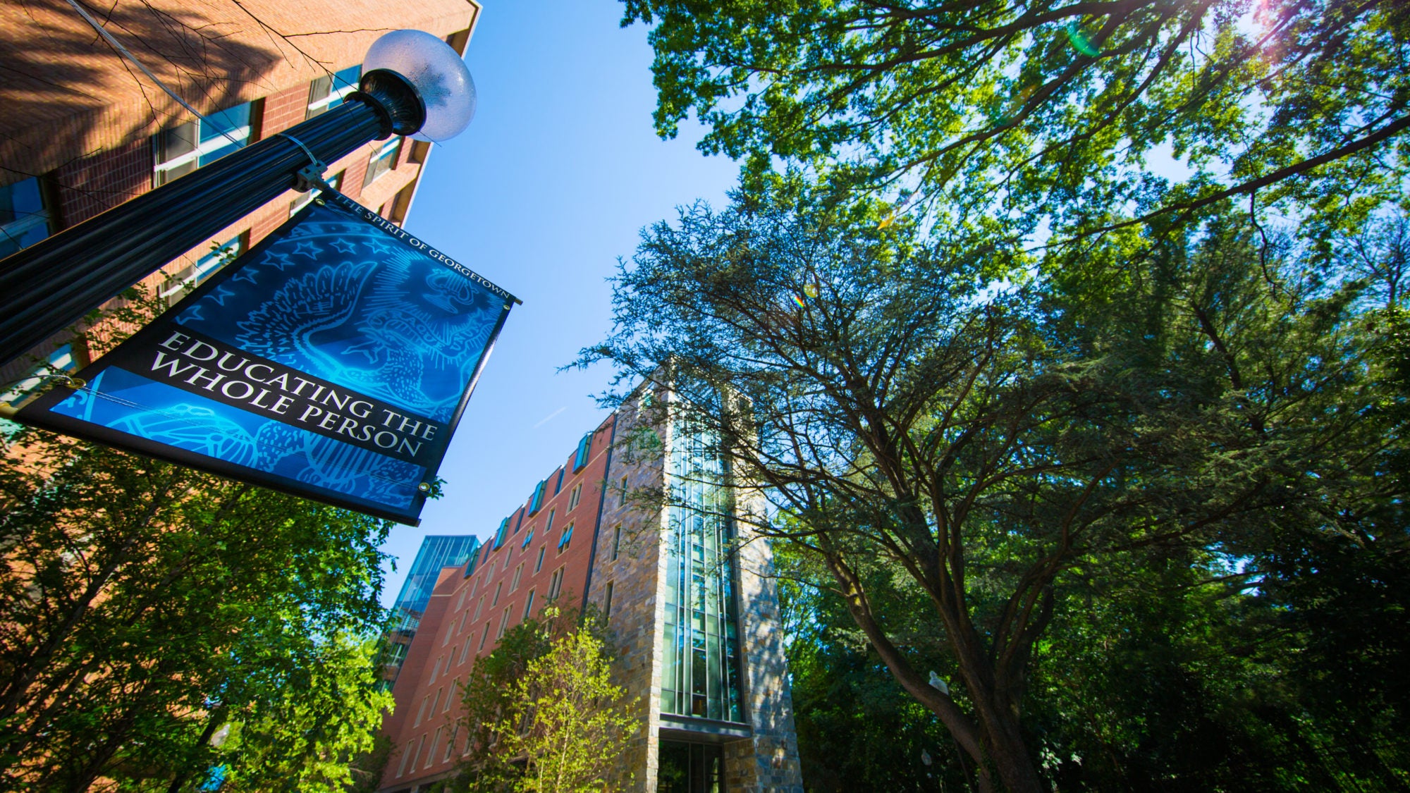 The image shows a banner that says &quot;Educating the Whole Person&quot; which hands in front of Arrupe Hall.