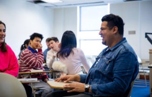 Juan Manuel Menjívar sits and talks with with students in class. 