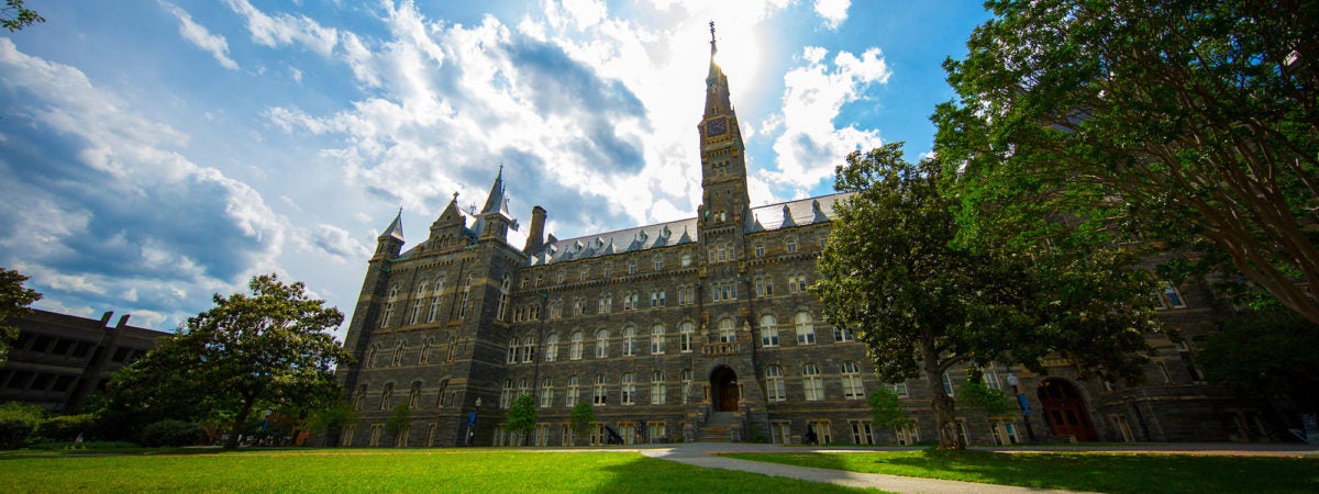 Healy Building with clouds behind it and a green lawn in front of it