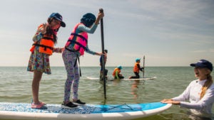 Emi Koch teaches two children how to surf.