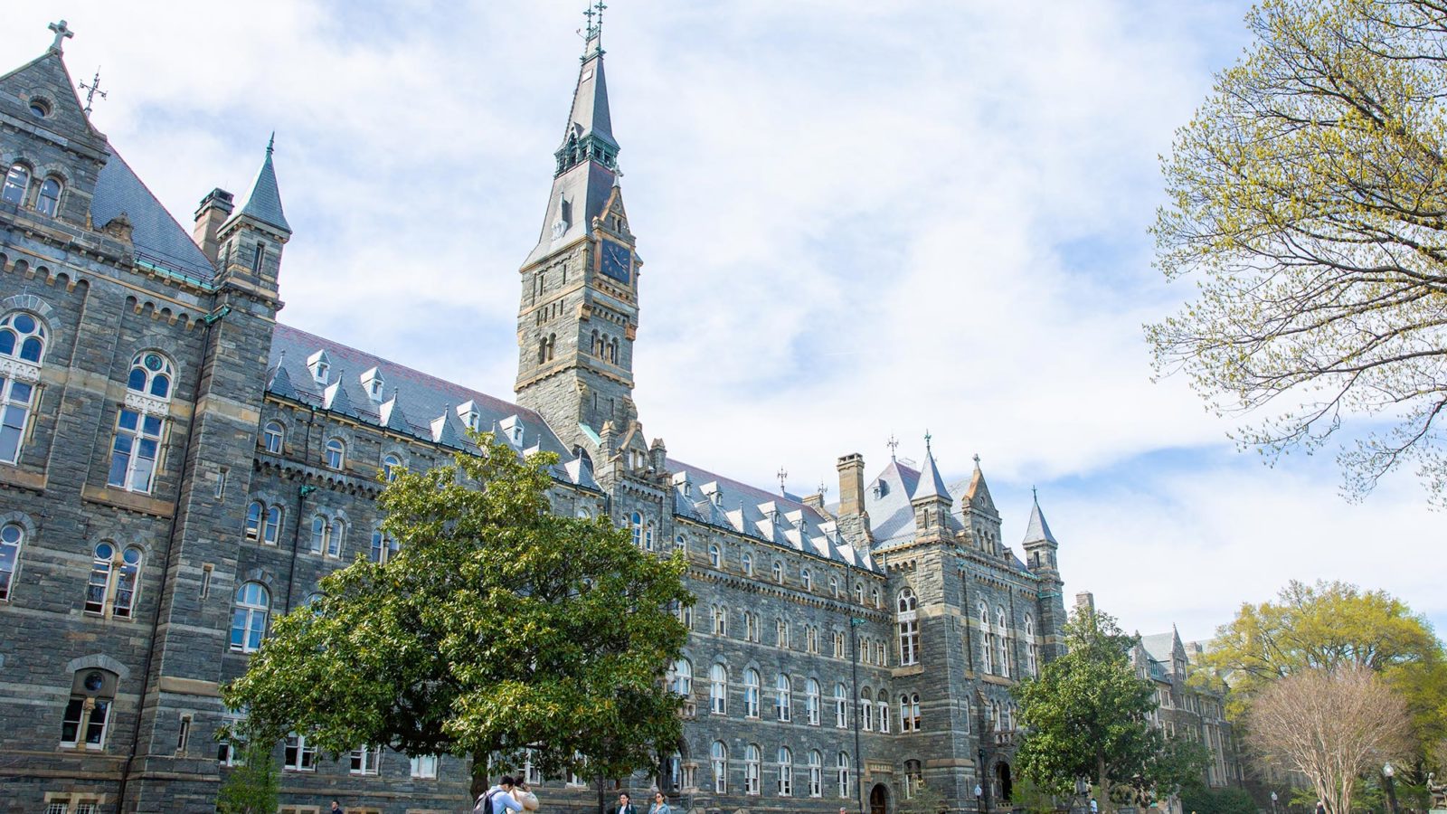 View of Healy Hall from the left of the building on a spring day with white clouds covering most of a blue sky