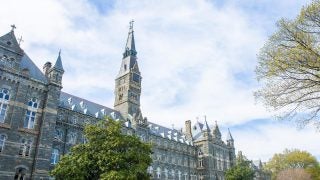 View of Healy Hall from the left of the building on a spring day with white clouds covering most of a blue sky