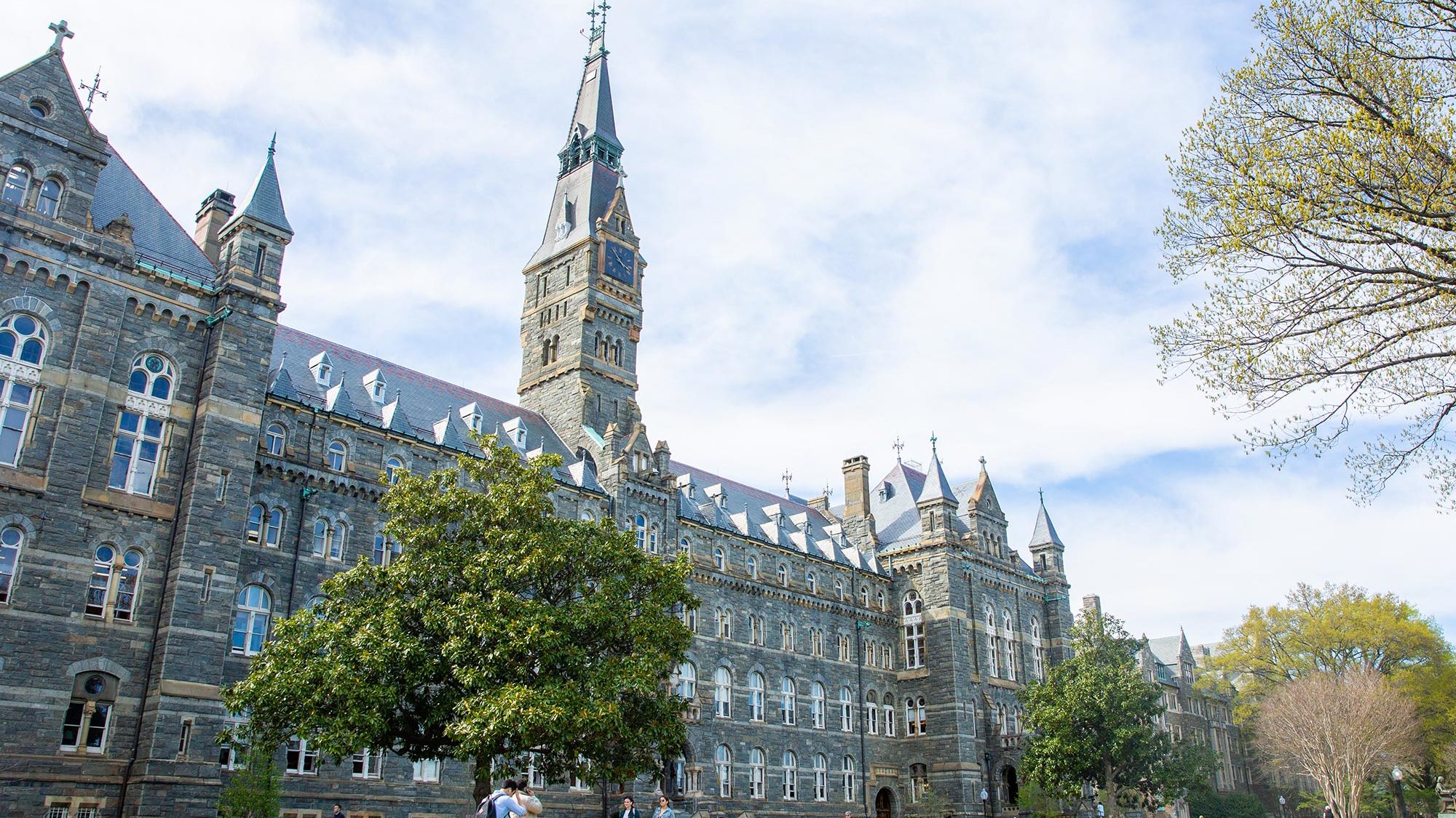 Students sit on the lawn in front of Healy Hall on a sunny day