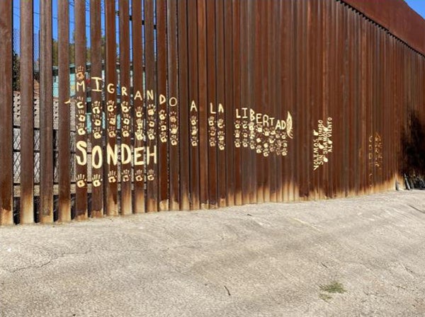 The wall at the border of the United States and Mexico with the Spanish words for migrating to freedom