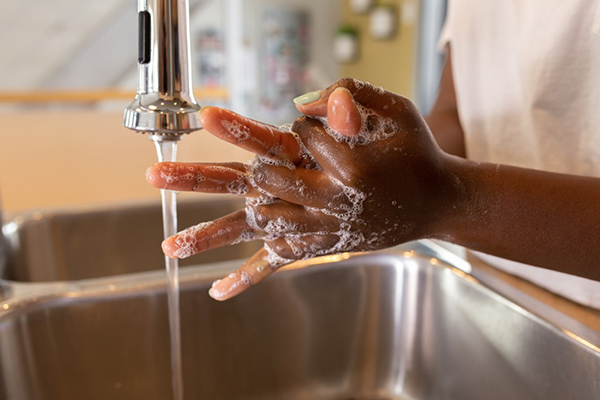 Woman of color washing her hands in a sink with running water