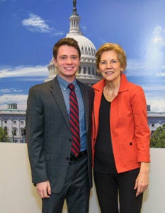 David Yellen and Elizabeth Warren pose together in front of a poster of the U.S. Capitol building.