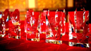 Glass awards sit on a red velvet cloth on a table.