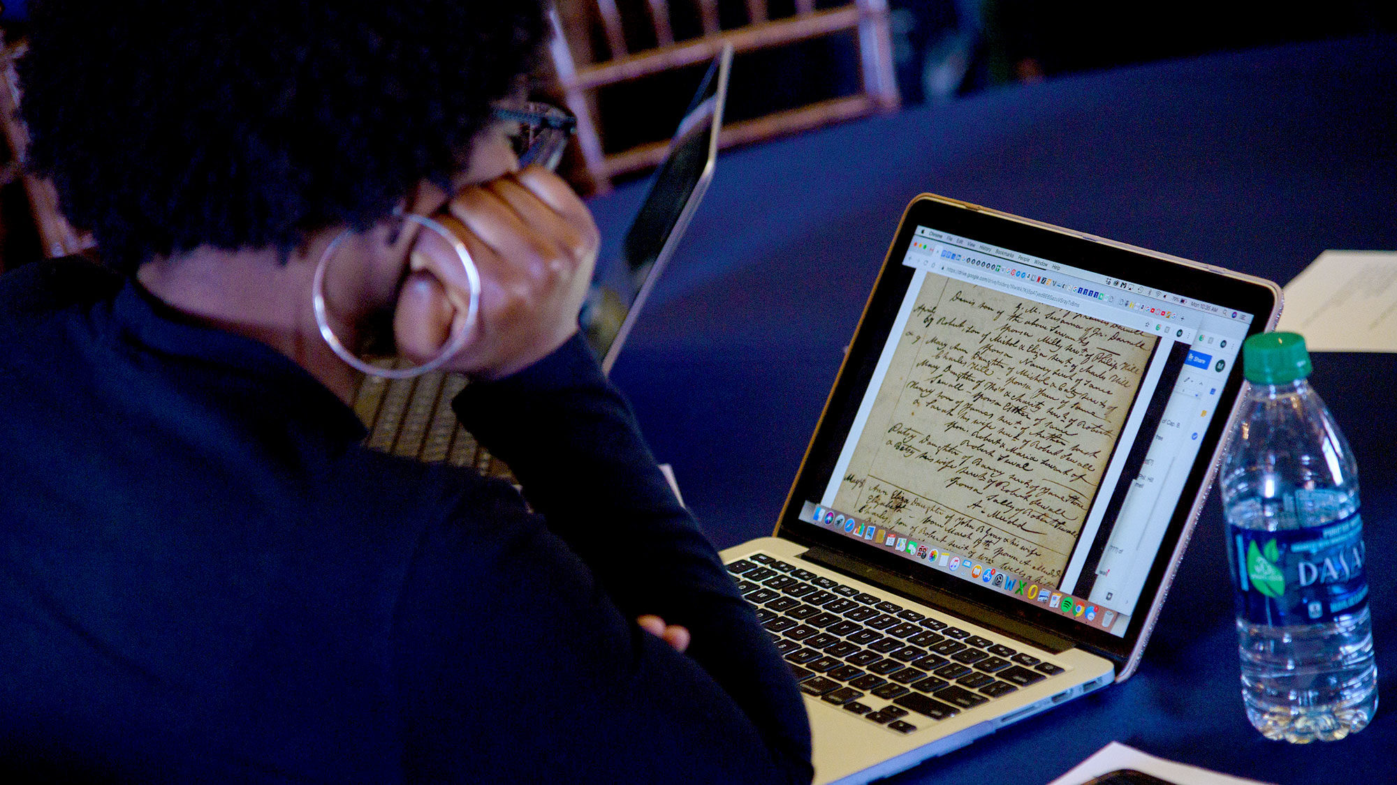 A woman looks at a historical document on her laptop computer.
