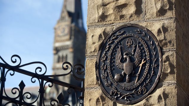 The seal of Georgetown in stone at the gates of the Healy Building, shown in background
