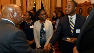 John Lewis shakes hands with a male student as a female student looks on. 