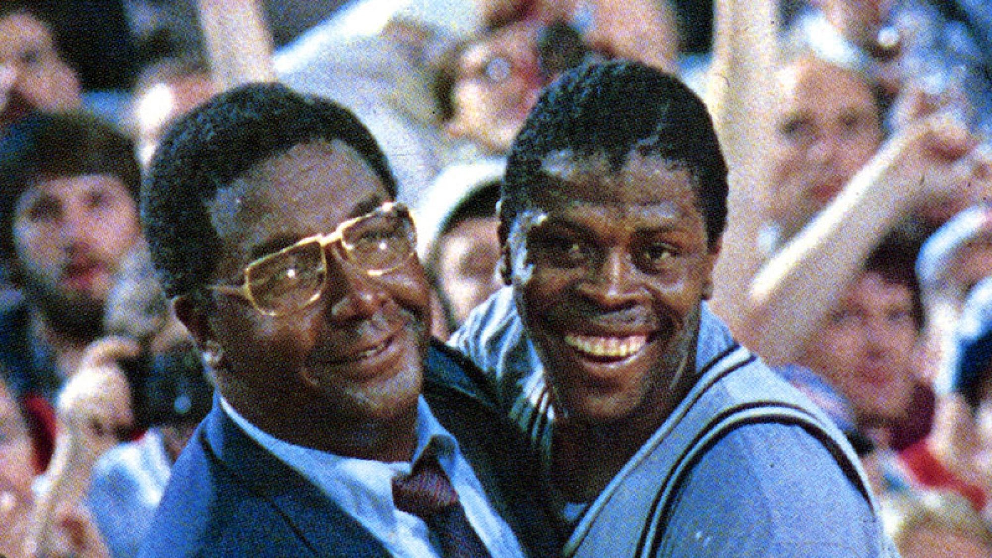 John Thompson Jr. and Patrick Ewing embrace in celebration on the court after a game.