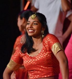 Ashanee Kottage dances on stage during Rangila wearing a read and gold costume.