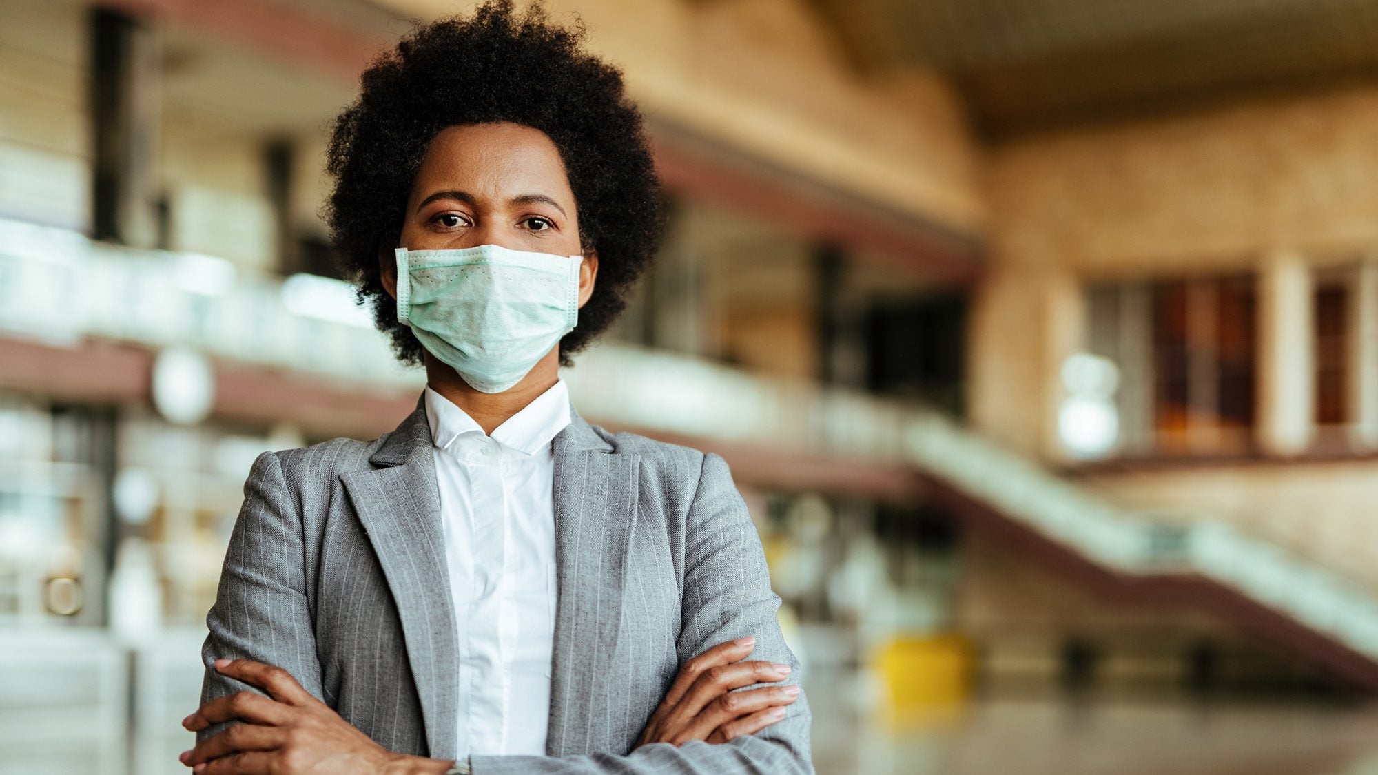 Woman standing with her arms folded wearing a mask