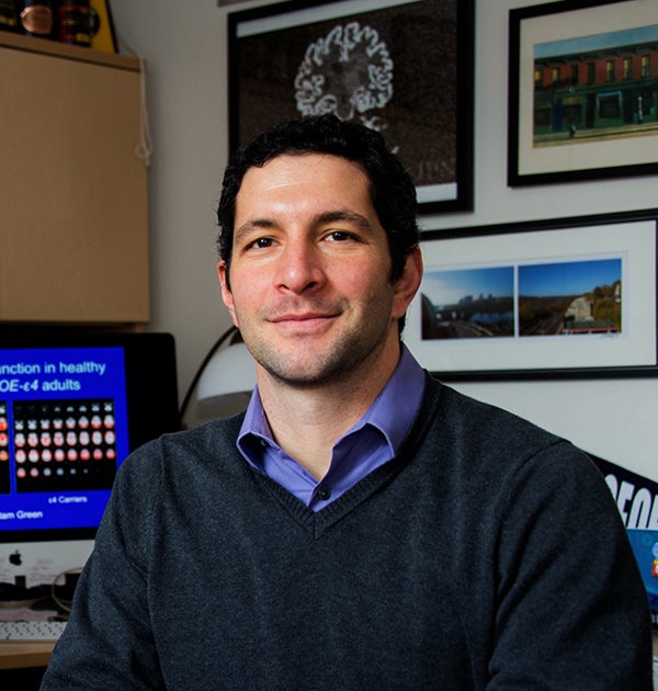 Adam Green in his office with a computer behind him and photos on the wall