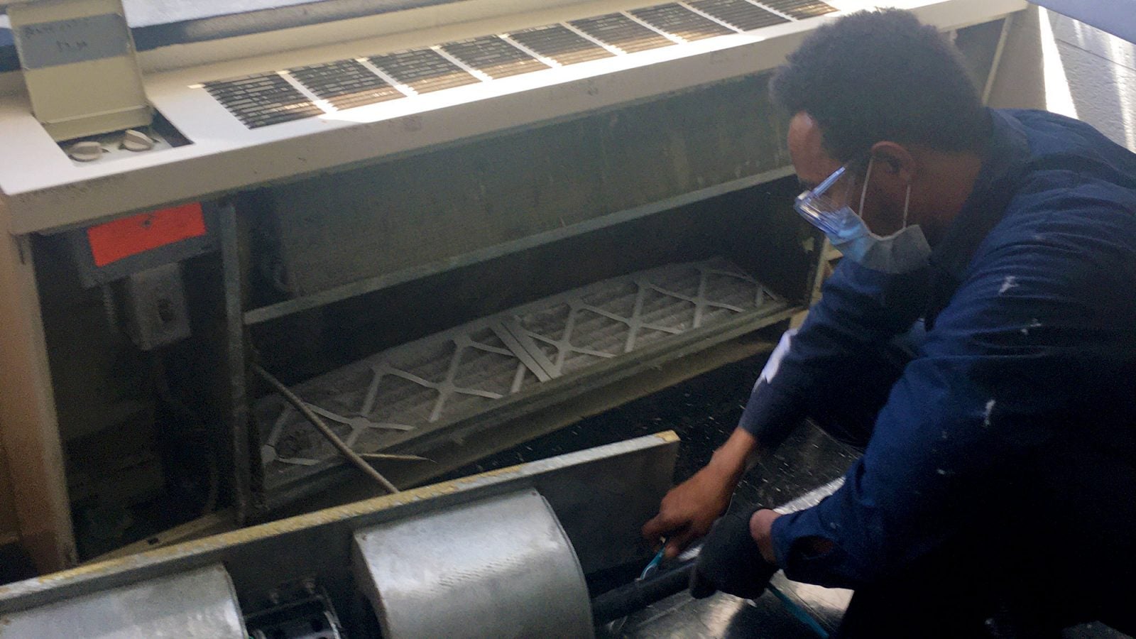 A man works on the heating and cooling unit in one of the reesidence halls.