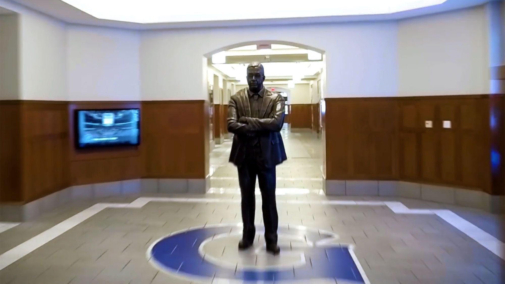 A bronze statue of john Thompson Jr. stands in the middle of the Georgetown Athletics logo inside the Thompson Athletic Center.