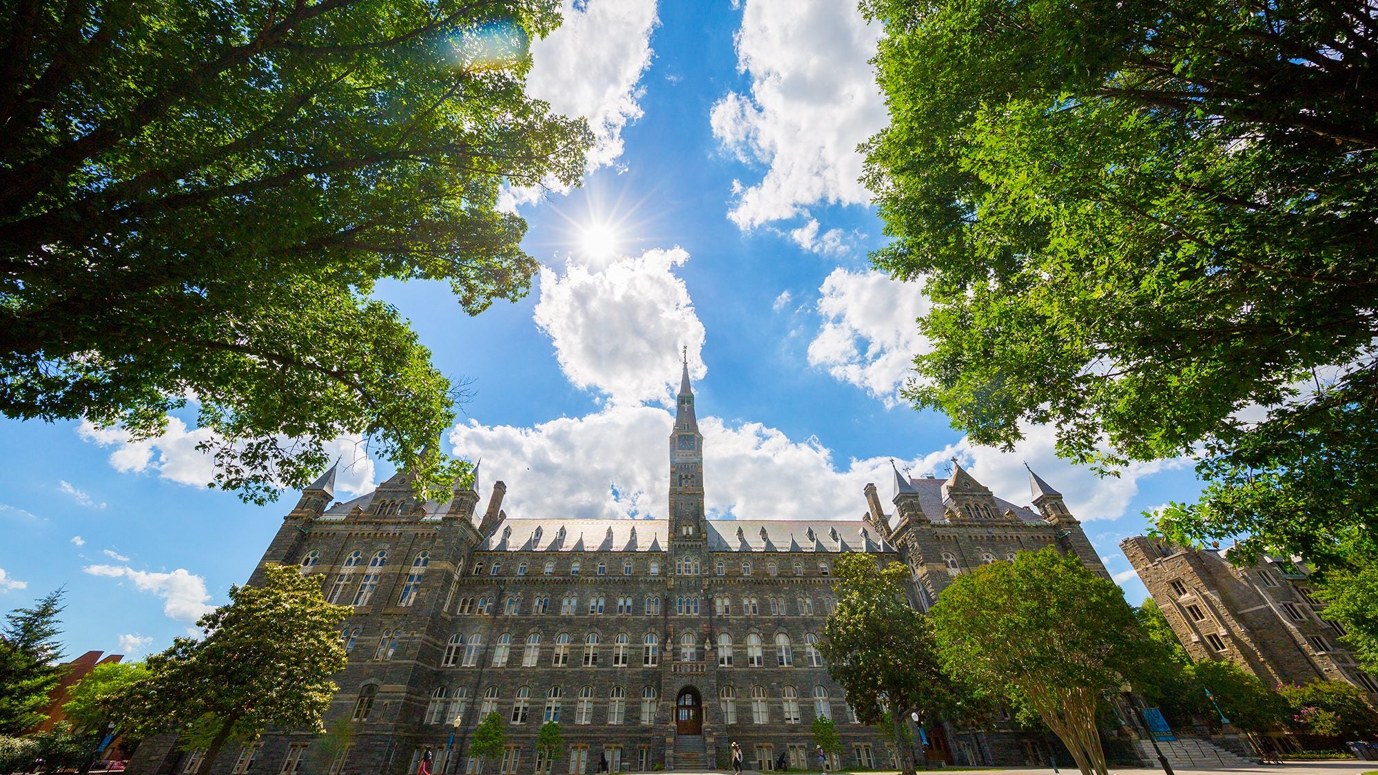 Healy Building with clouds behind it and a green lawn in front of it