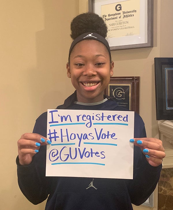 Sari Cureton holds up a sign reading "I'm registered #HoyasVote @GUVotes 