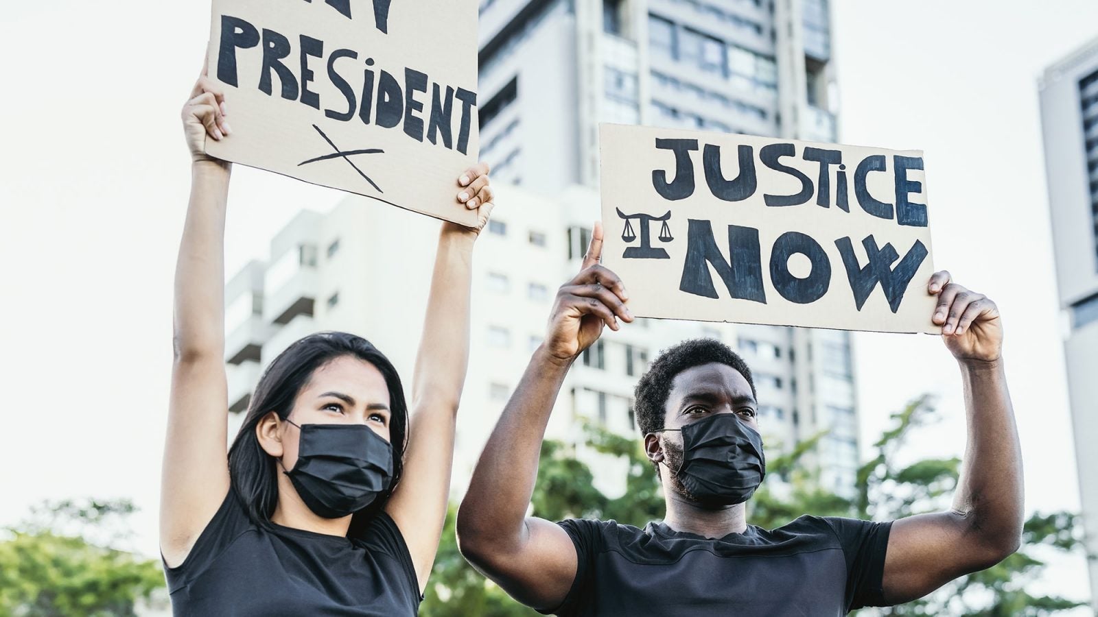 Two demonstrators hold up signs that read &quot;President&quot; and &quot;Justice Now.&quot;