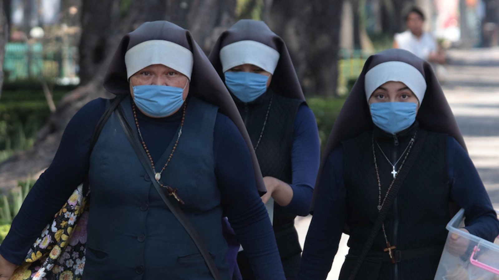 A group of nuns walk while wearing masks.