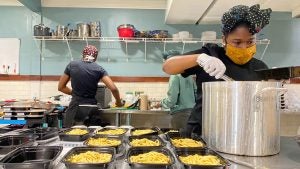 Three people prepare food in an open kitchen.