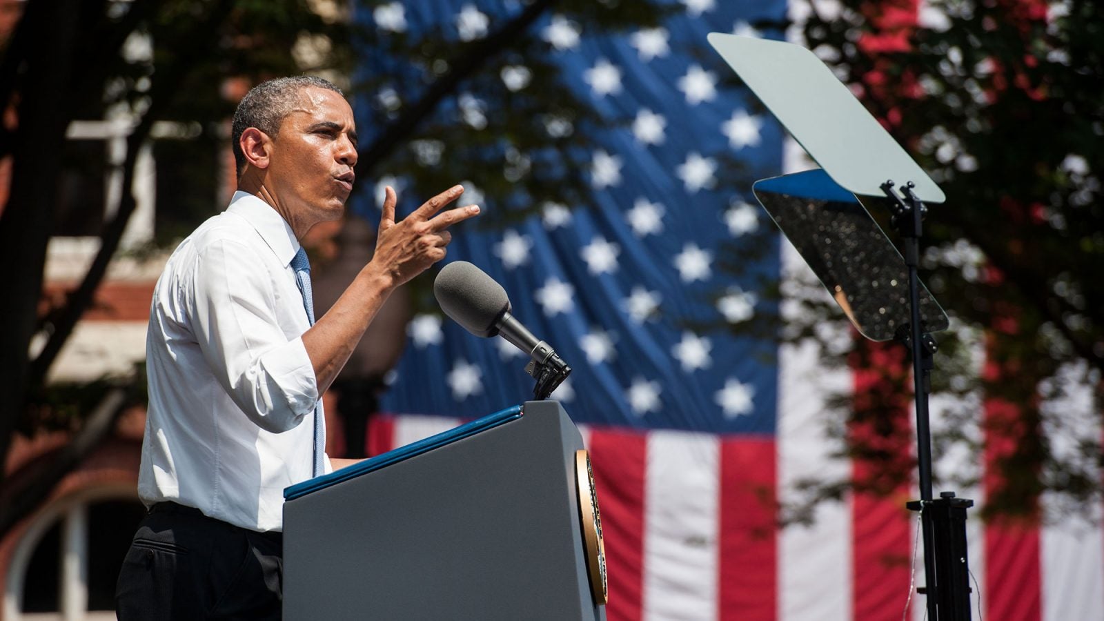 A side view of Barack Obama as he stands at a lectern delivering an address outside.