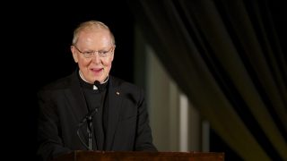 Father Leo J. O&#039;Donovan speaks at a podiium