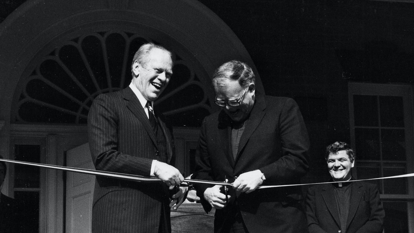 A black and white photo of President Gerald Ford on the steps of the Old North Building with Father Timothy Healy