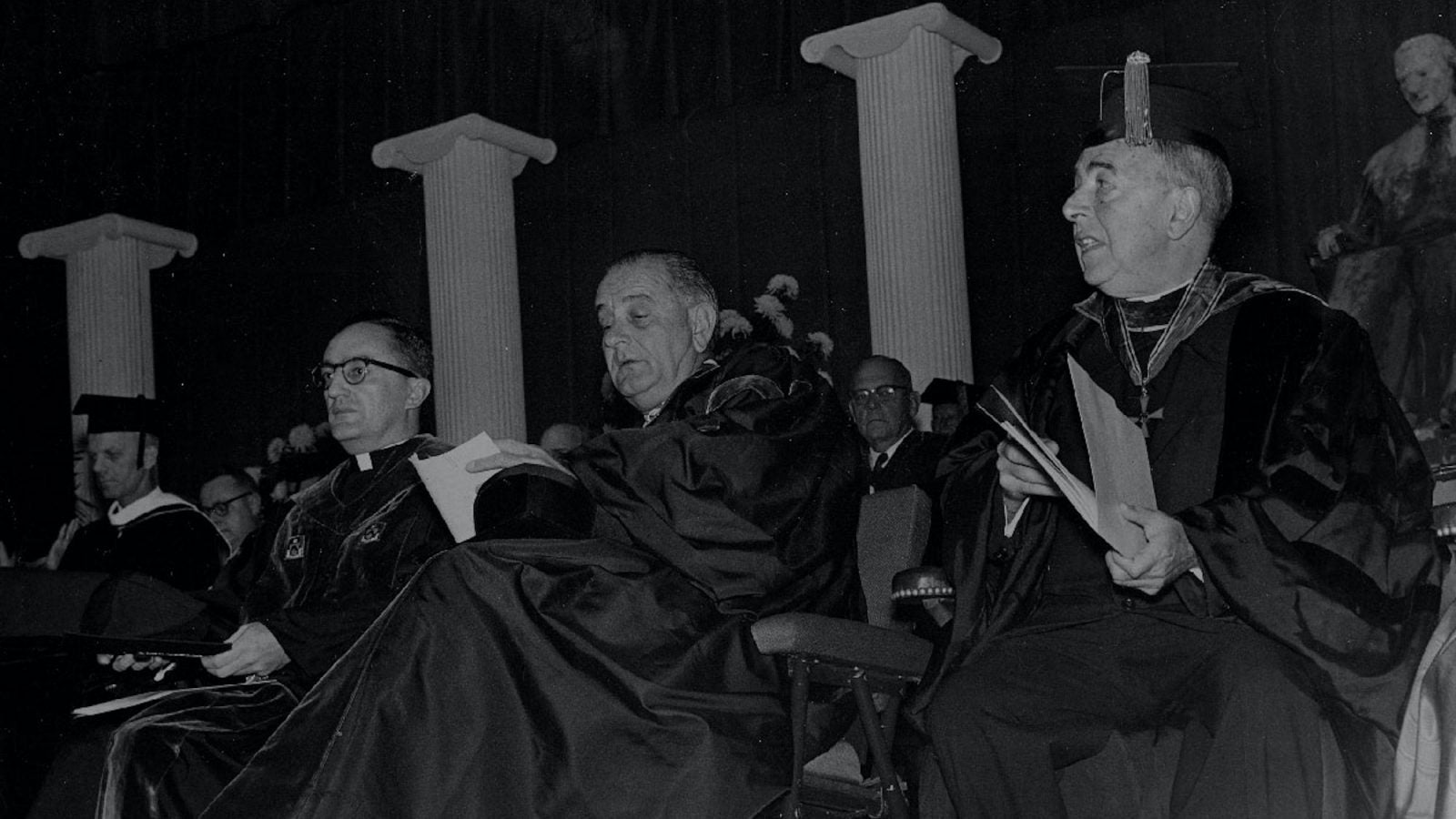 A black and white photo of President Lyndon Johnson at a Georgetown ceremony with faculty in academic robes