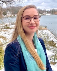 Kate Barranco in an outdoor photo standing in front of trees and water