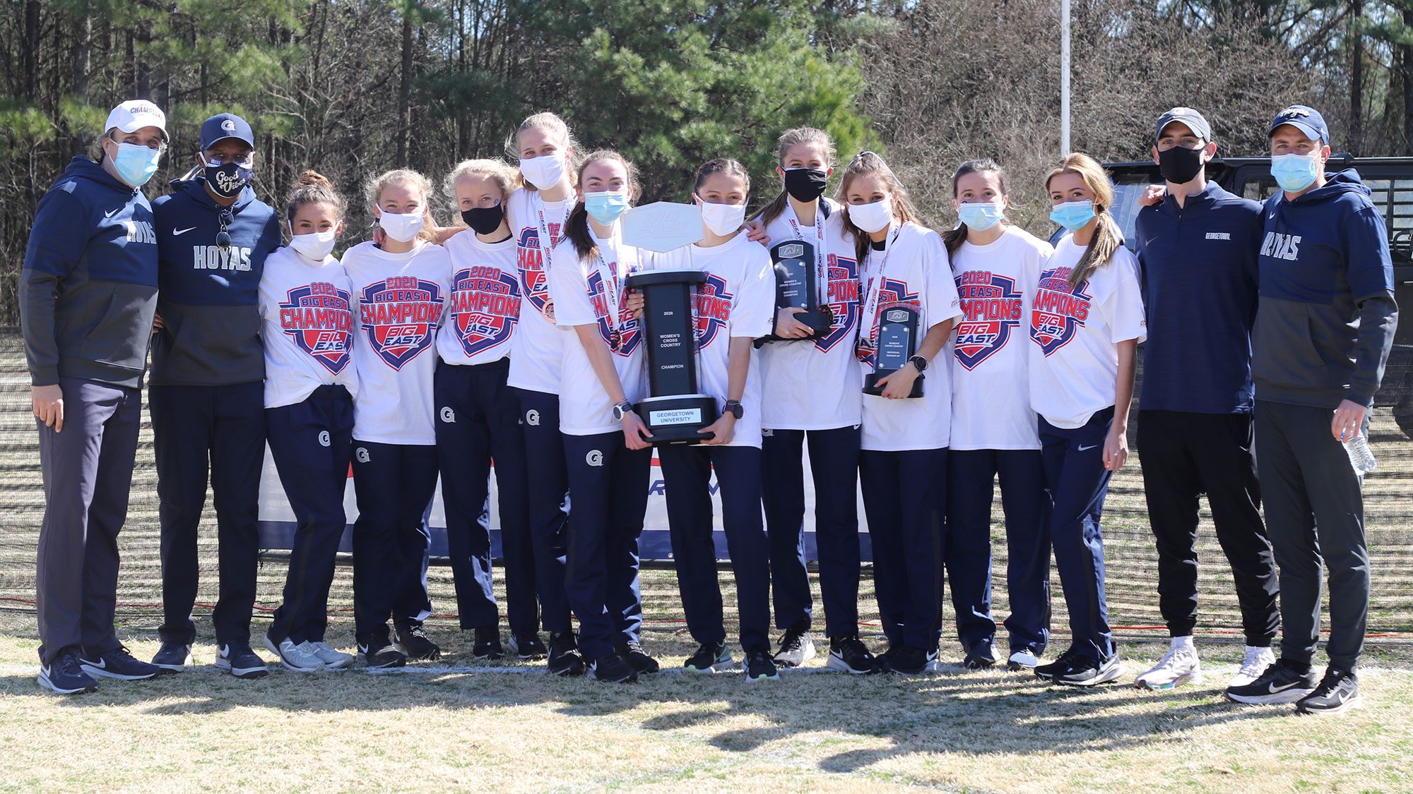 The women&#039;s cross country team and coaches pose with the BIG EAST Championship trophy.