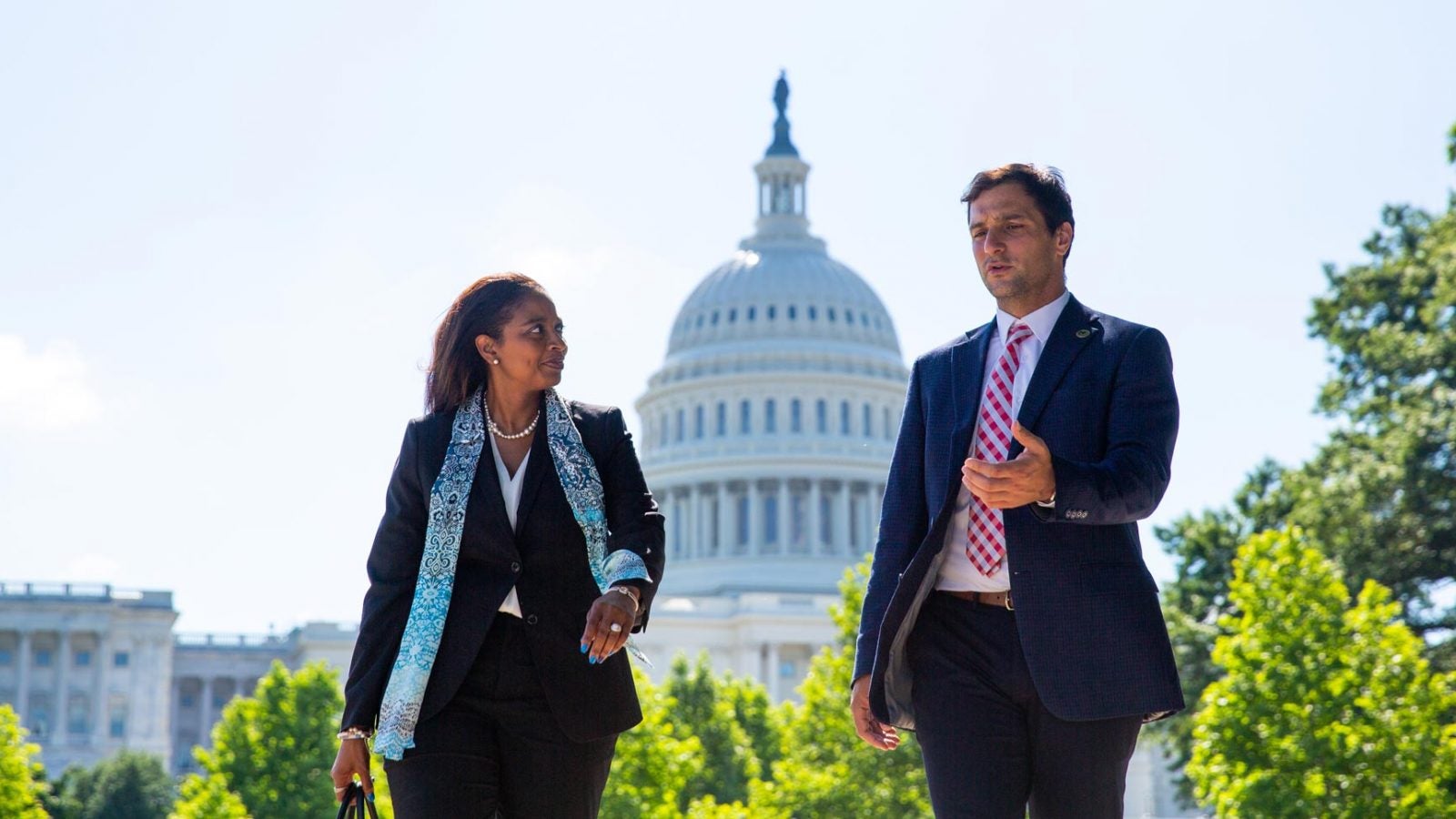 Woman and man in business clothes walk in front of the Capitol Building