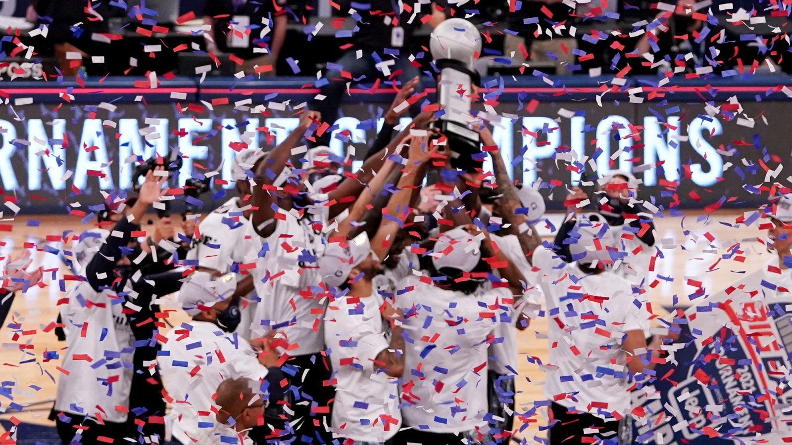 The men&#039;s basketball team celebrate on the court after winning the BIG EAST championship as confetti falls.