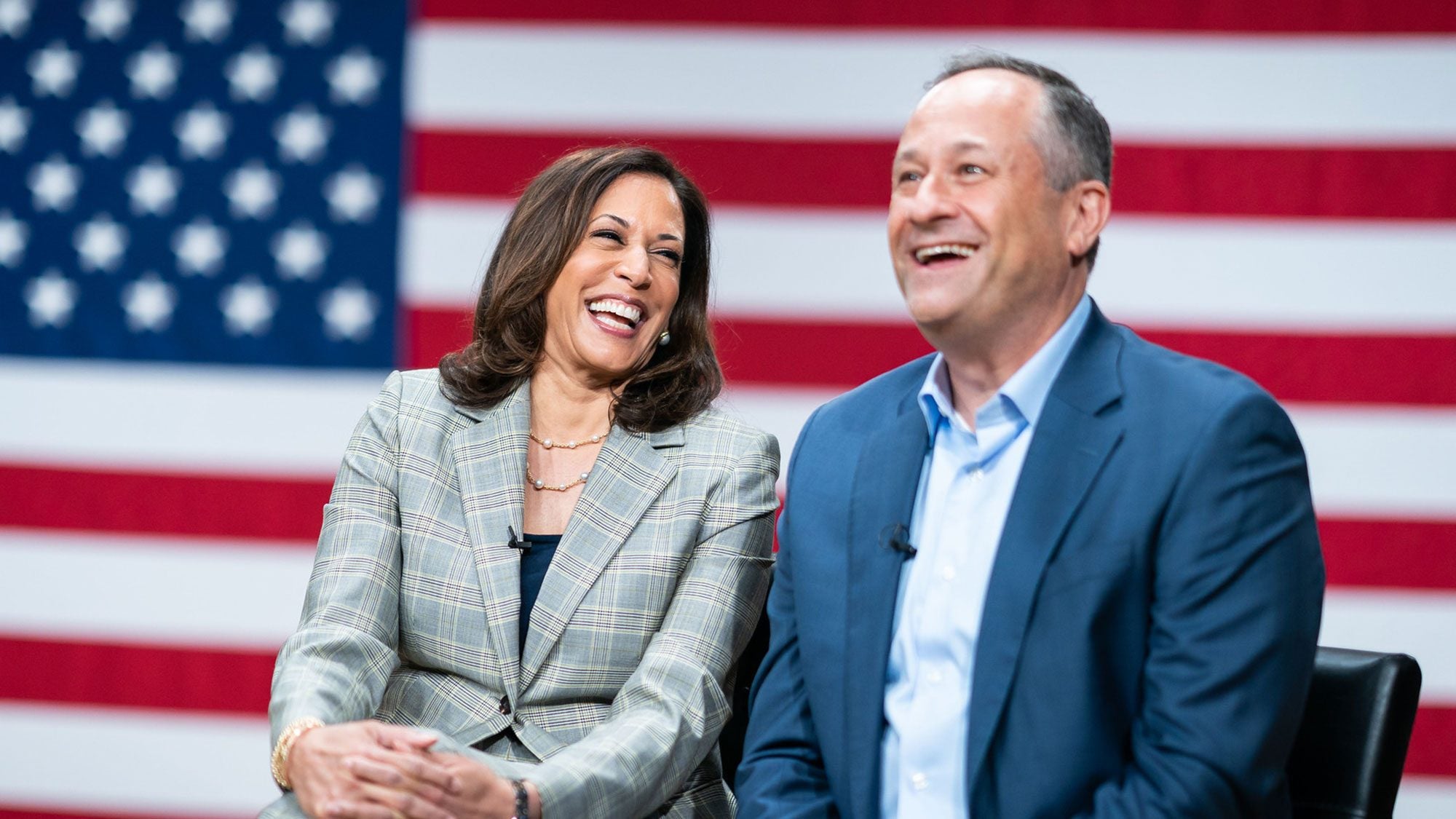 Kamala Harris and Douglas Emhoff share a laugh with the American flag in the background.