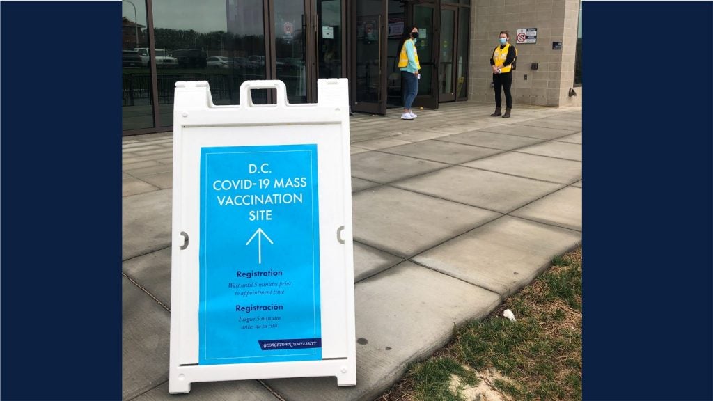 A sign guides people toward the arena to get their vaccines.