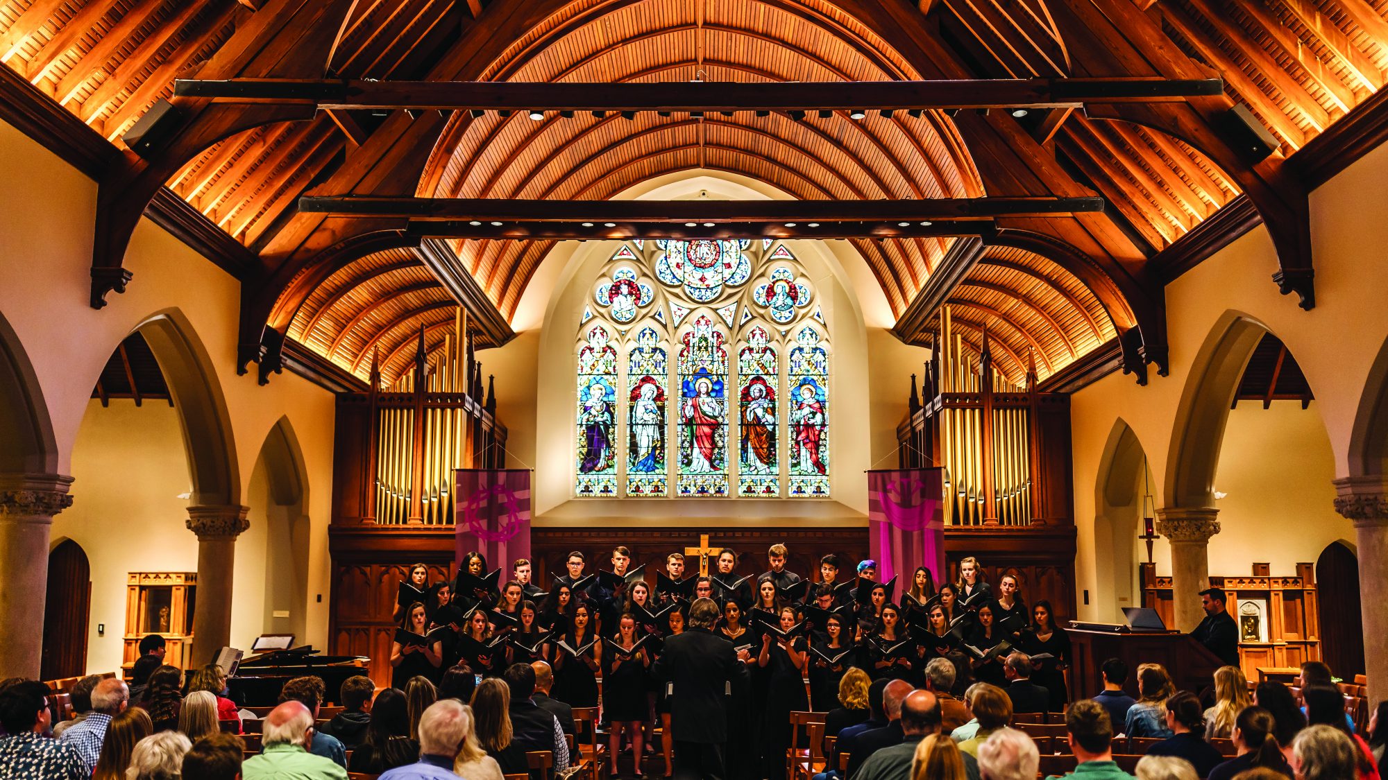 The GU Concert Choir with Prof. Frederick Binkholder, Music Director, performs in front of the stained glass window in Dahlgren Chapel, to a full congregation.