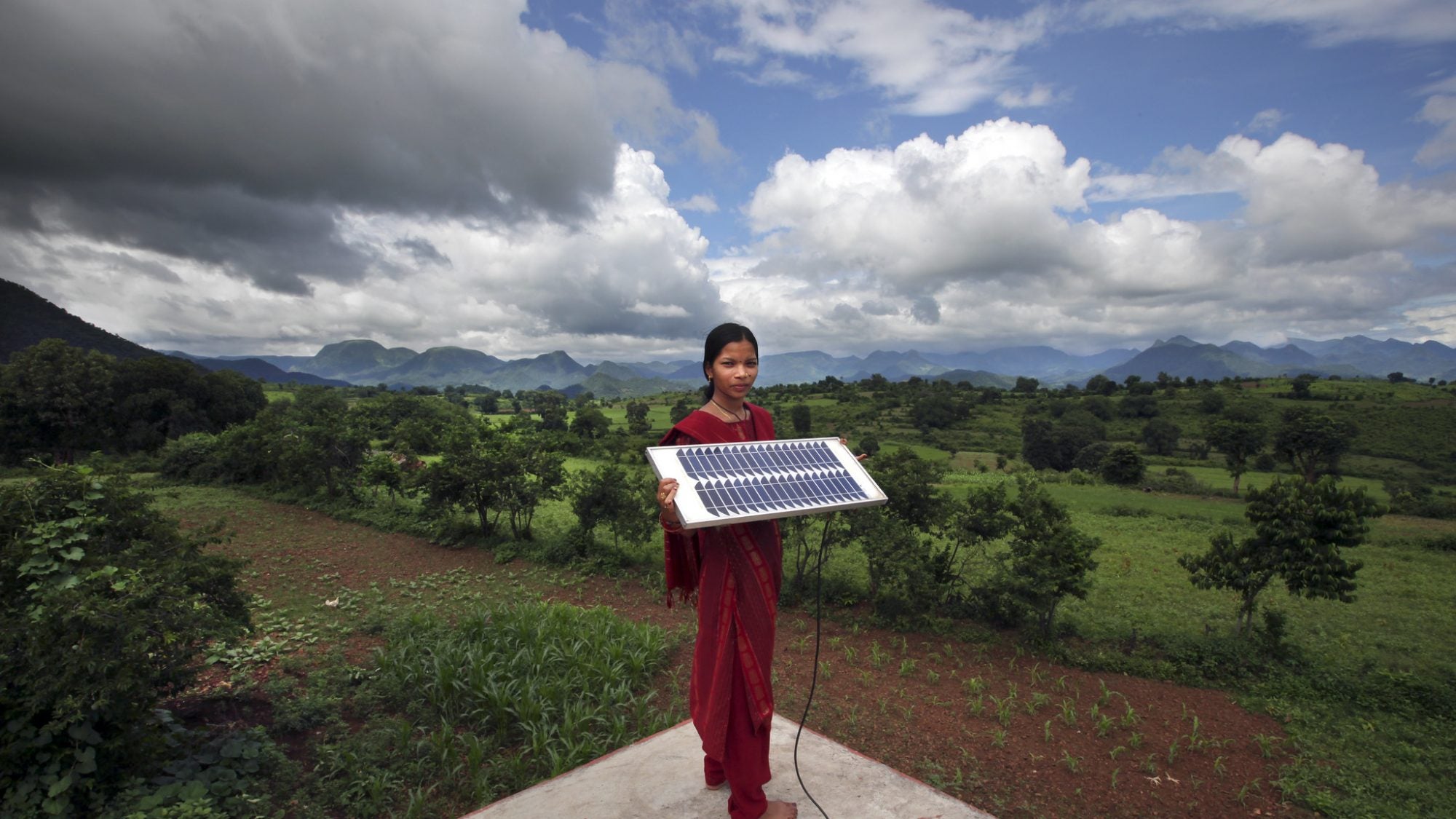 Girl holds solar panel in front of farm land